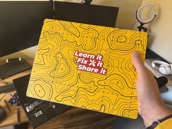 Bright yellow laptop cover with red and white bold sticker that says Learn It, Fix It, Share It.