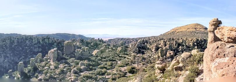 Sweeping panorama from high elevation of a sea of ball rocks and boulders and chimney stacks dotting the mountainous desert landscape.