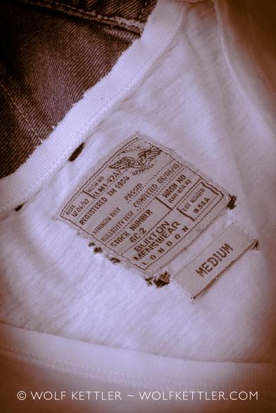 Close-up of an old T-shirt with small holes and frayed at the edges.